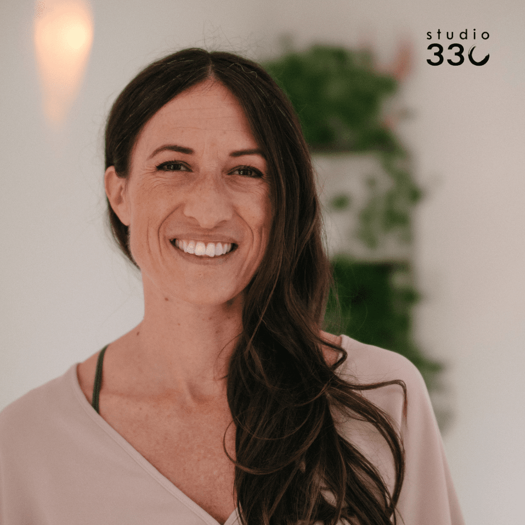 Headshot of Miriam smiling standing in front of a blurred out plant