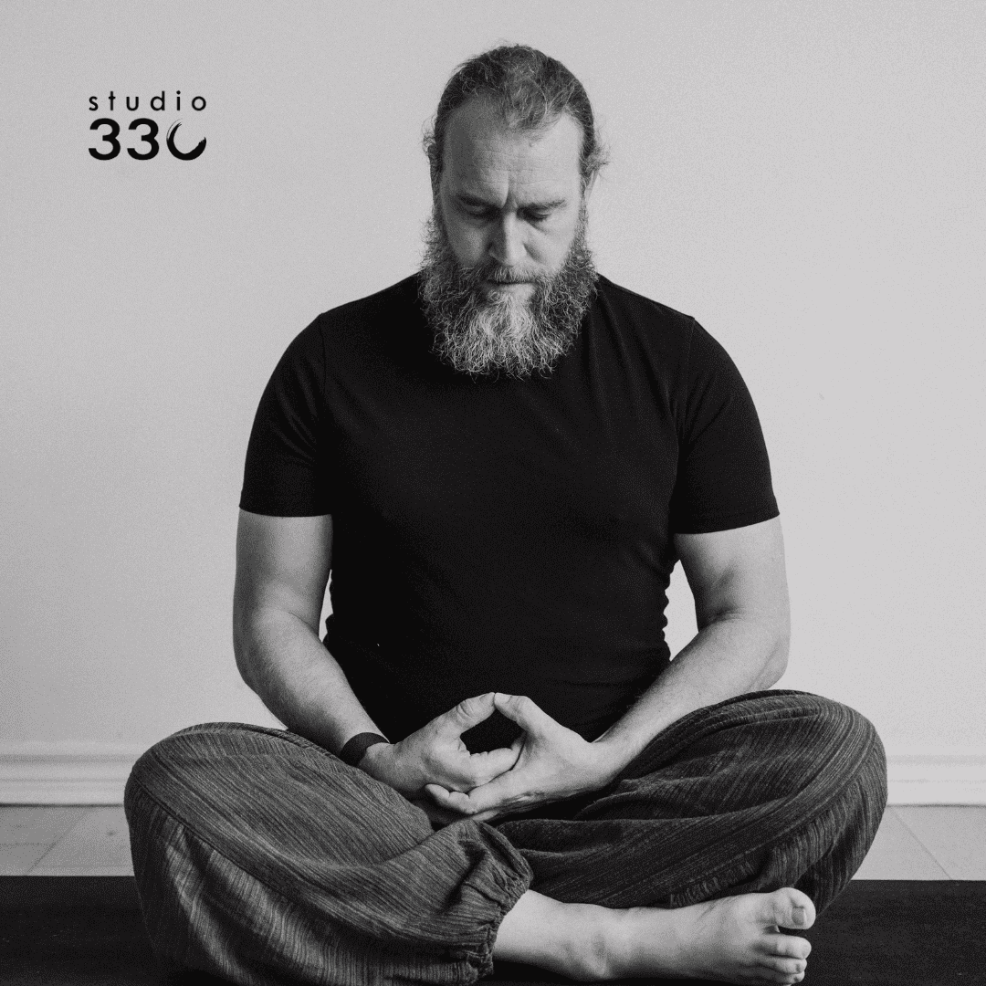 Black and white photo of Nathan sitting in meditative pose